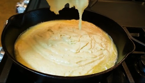 Pour the cornbread batter into the skillet and spread it evenly.