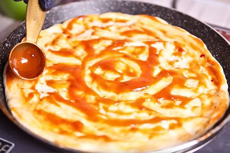 Spread a generous layer of pizza sauce over the dough
